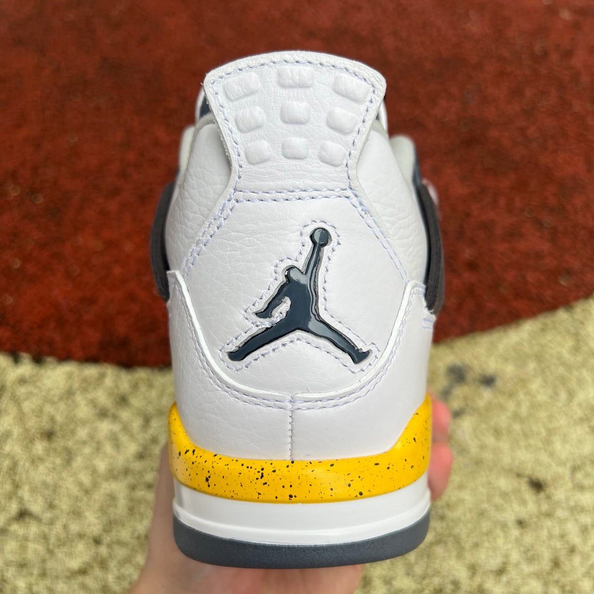 Close-up of Nike x Jordan Air Jordan 4 Retro Rare Air Tour Yellow sneakers showing yellow and black color details and textured materials.
