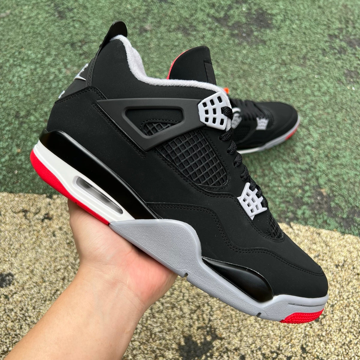 Nike Air Jordan 4 Retro OG Bred sneakers in black and red with white accents, showing the iconic design and Nike branding.