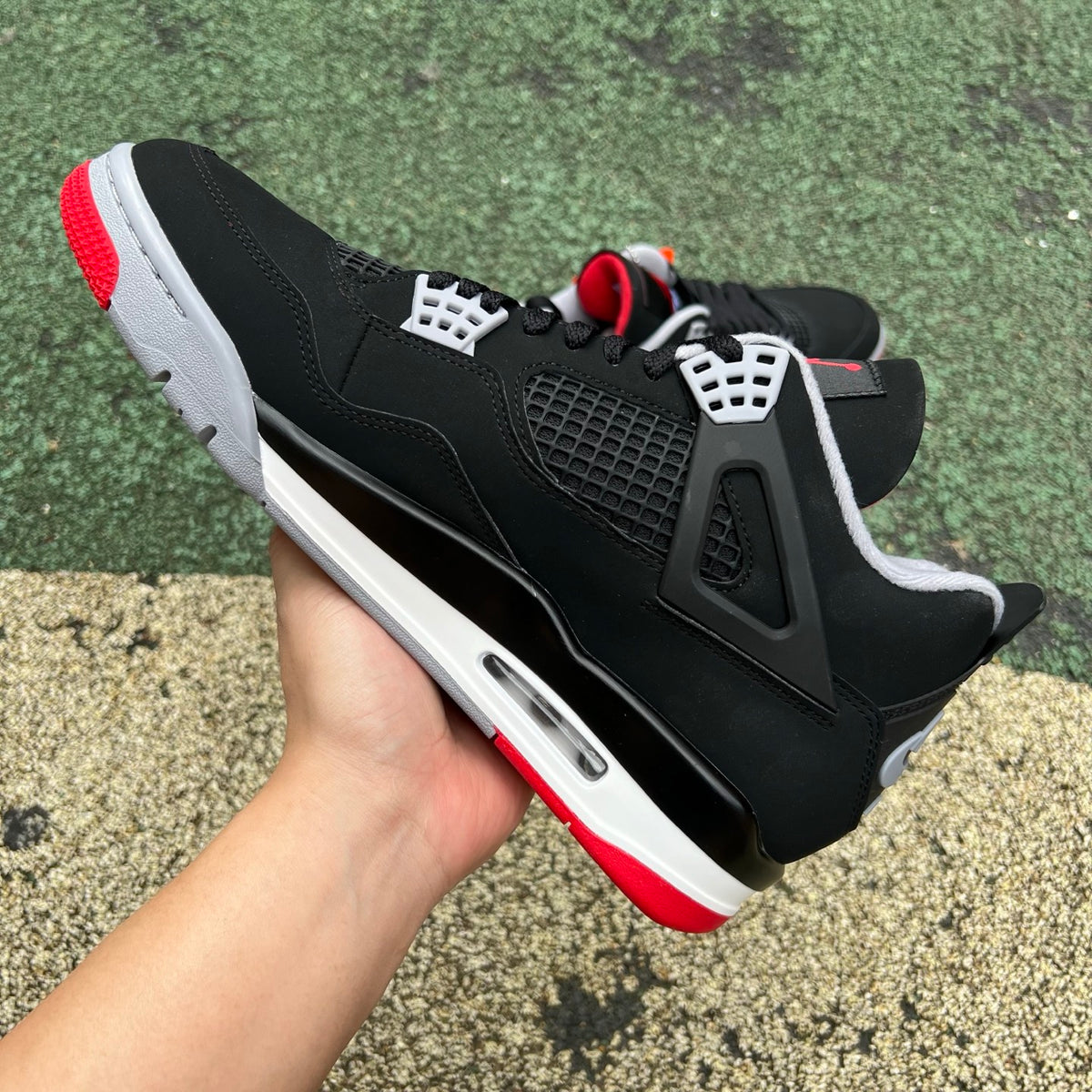 Close-up of Nike Air Jordan 4 Retro OG Bred sneakers featuring black and red colorway and classic design details.
