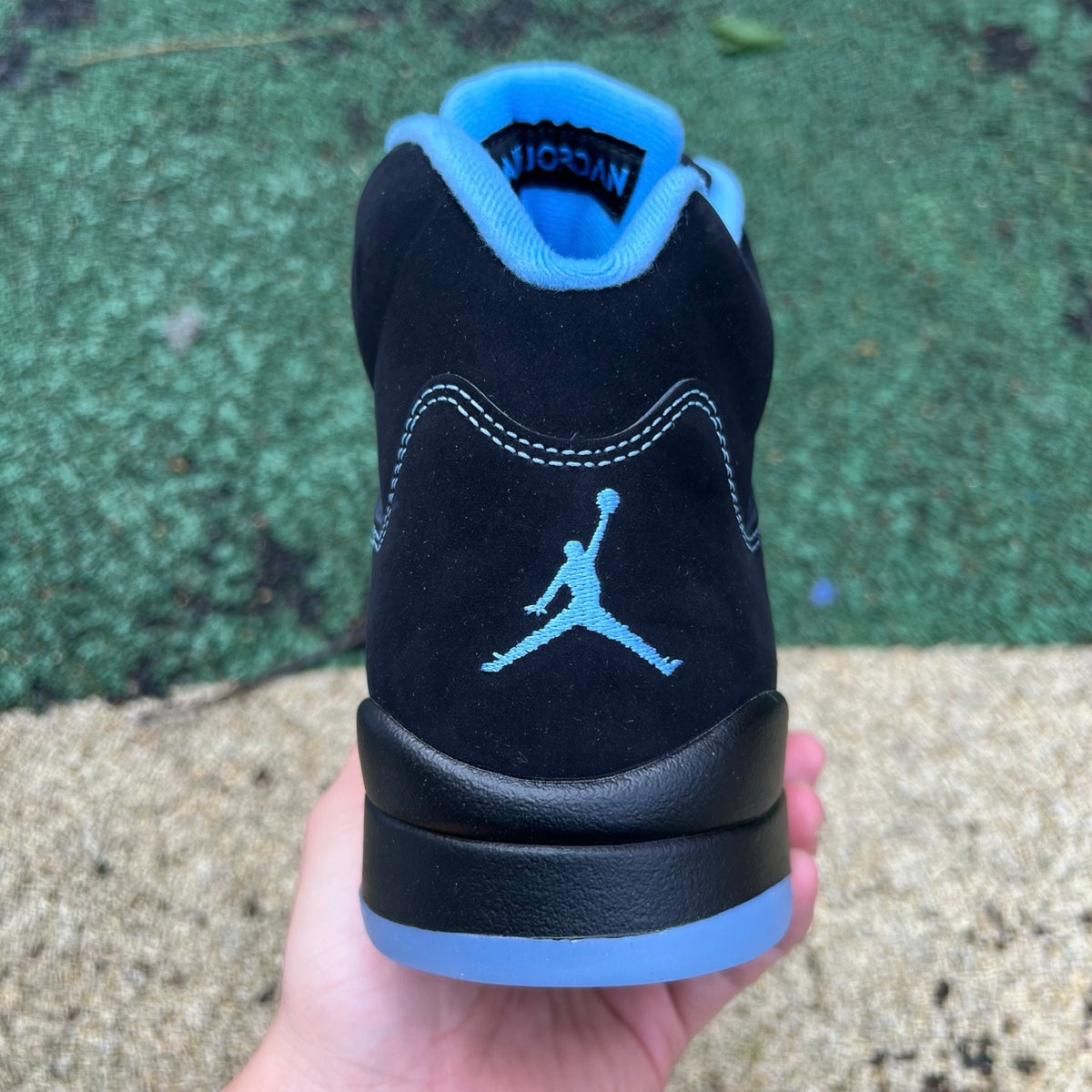 Nike Air Jordan 5 Retro sneakers in black and university blue, featuring a sleek design and iconic Jordan branding.