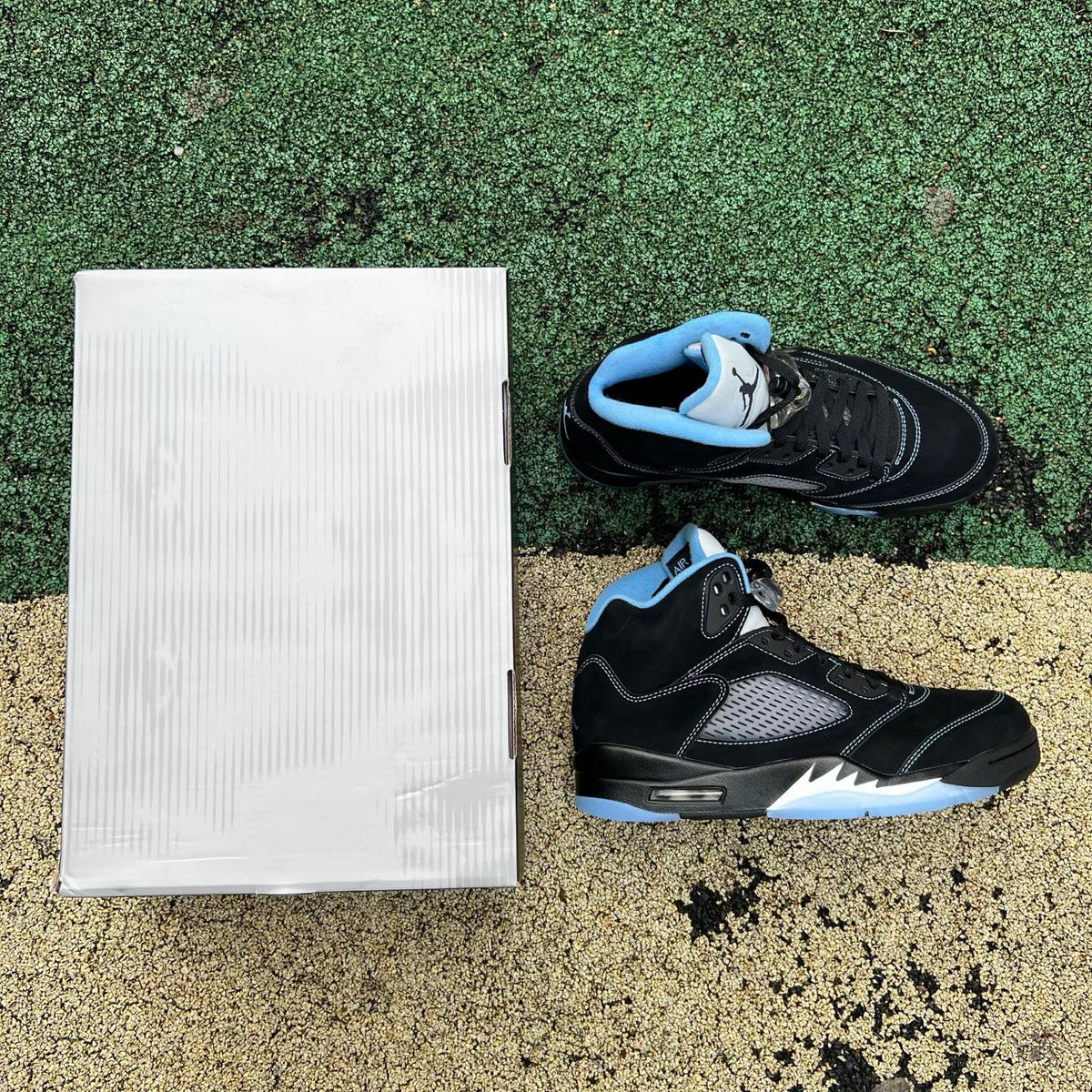 Nike Air Jordan 5 Retro sneakers in black and university blue, side view showing the iconic design and color accents.