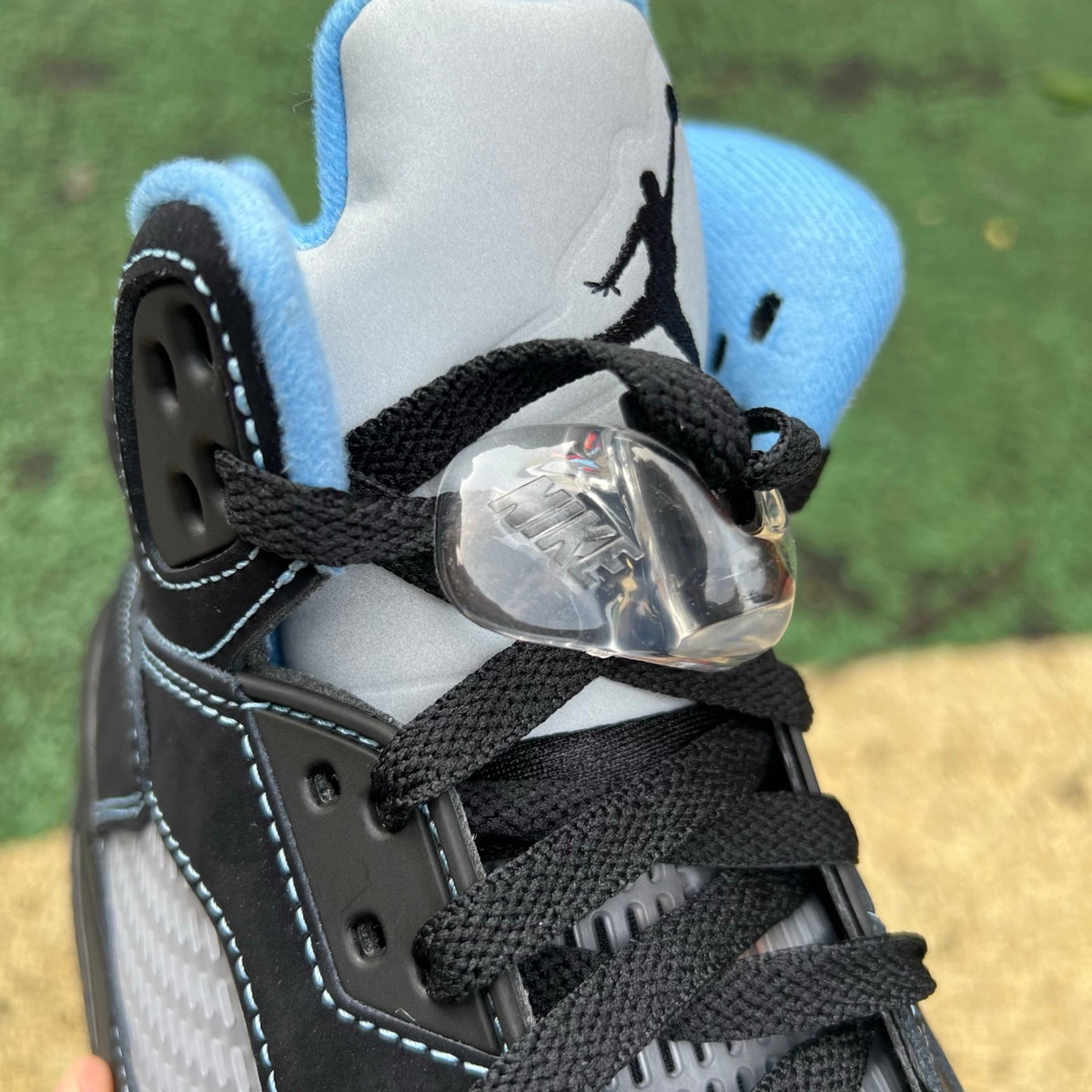 Nike Air Jordan 5 Retro sneakers in black with university blue accents, featuring a classic design and iconic Jordan branding.