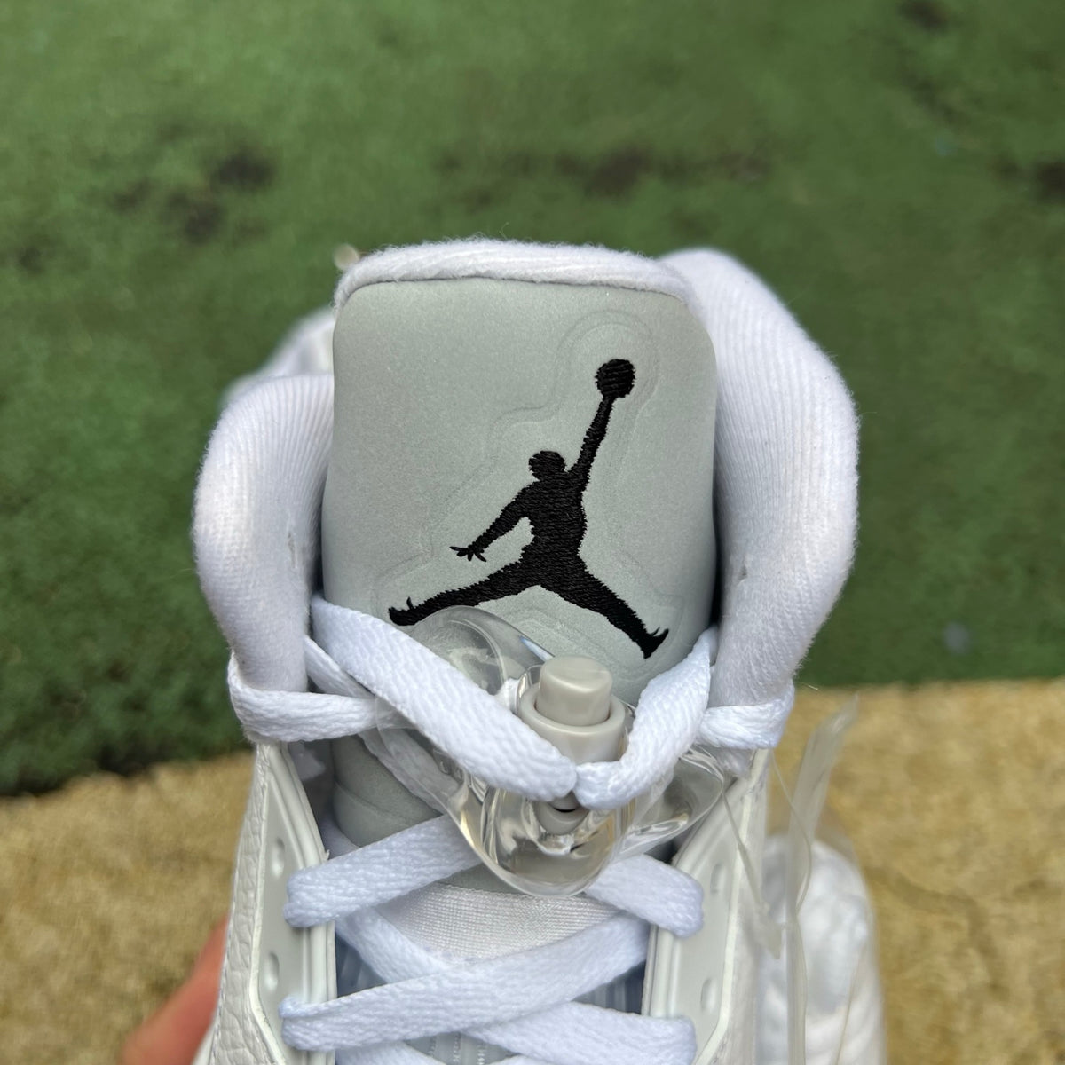White Nike Air Jordan 5 Retro sneakers with metallic accents, detailed close-up of the Nike x Jordan shoe.