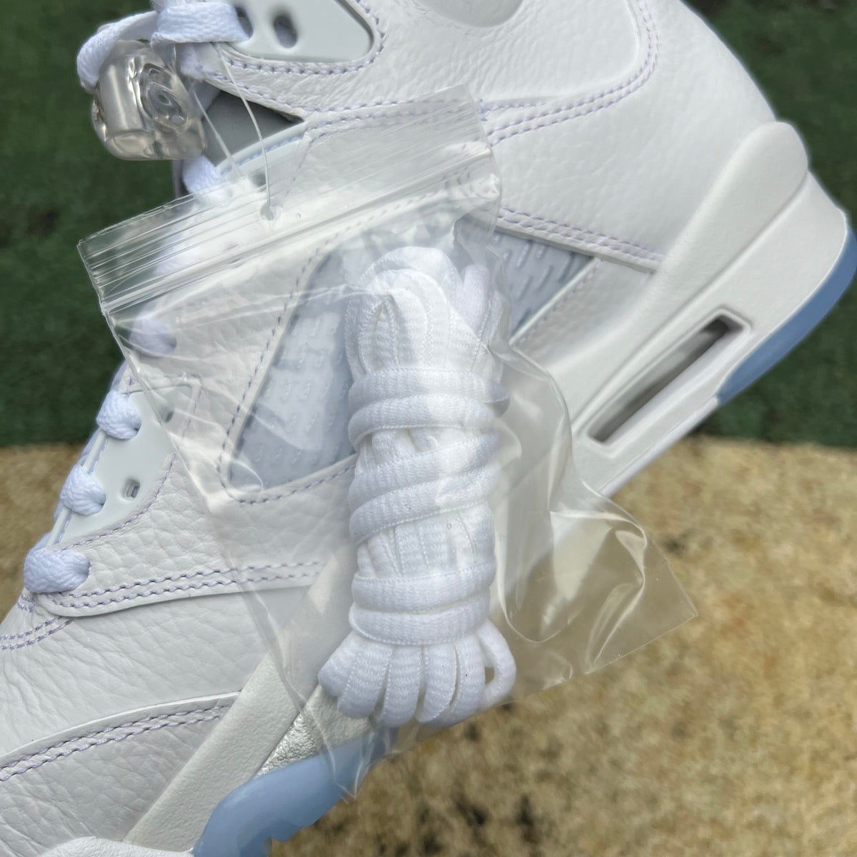 Close-up of Nike Air Jordan 5 Retro White Metallic sneakers showing the white and metallic silver design details.