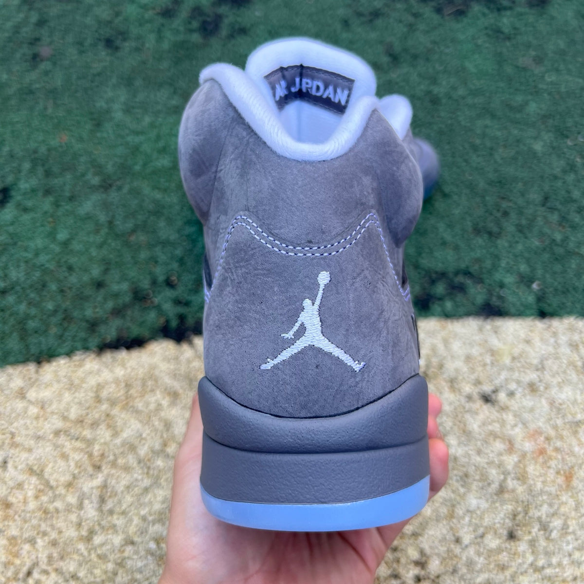 Nike Air Jordan 5 Retro Wolf Grey sneakers in a side view, showcasing the grey leather and signature design details.