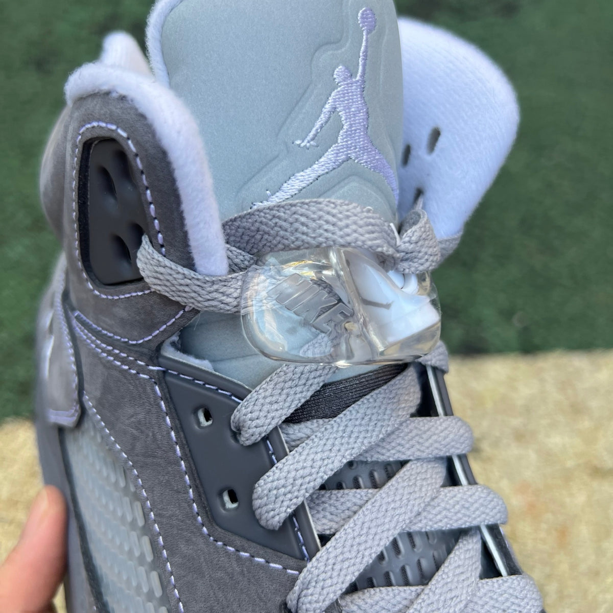 Nike Air Jordan 5 Retro Wolf Grey sneakers, featuring grey suede and plastic accents, on a white background.
