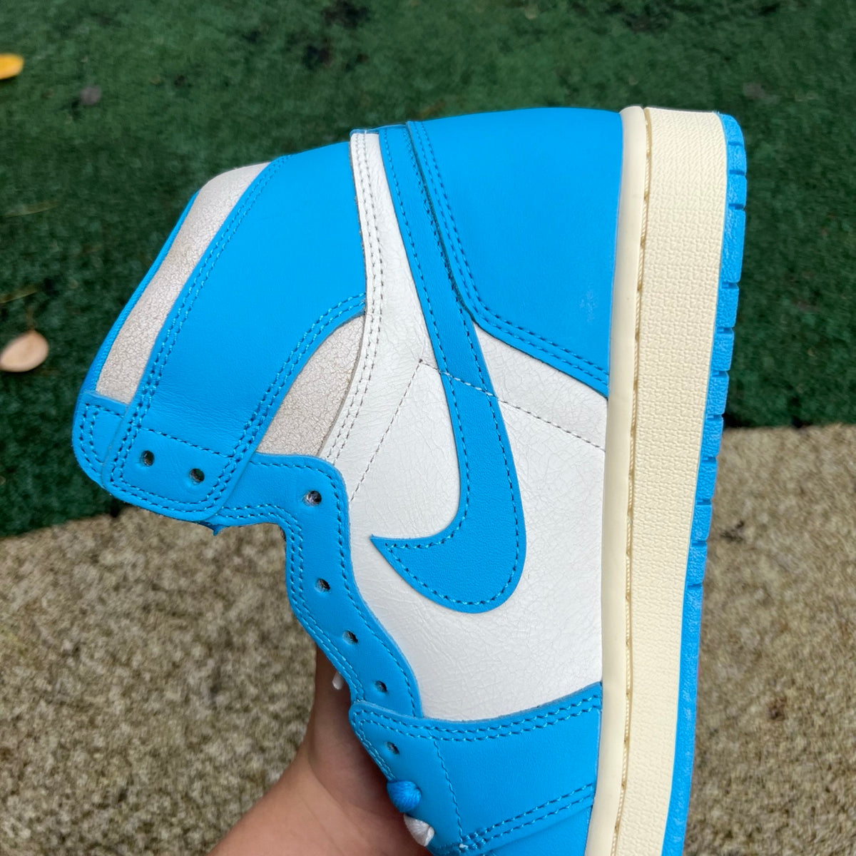 Nike Air Jordan 1 Retro High OG UNC Reimagined sneakers in white and blue leather with Nike swoosh and high-top design.