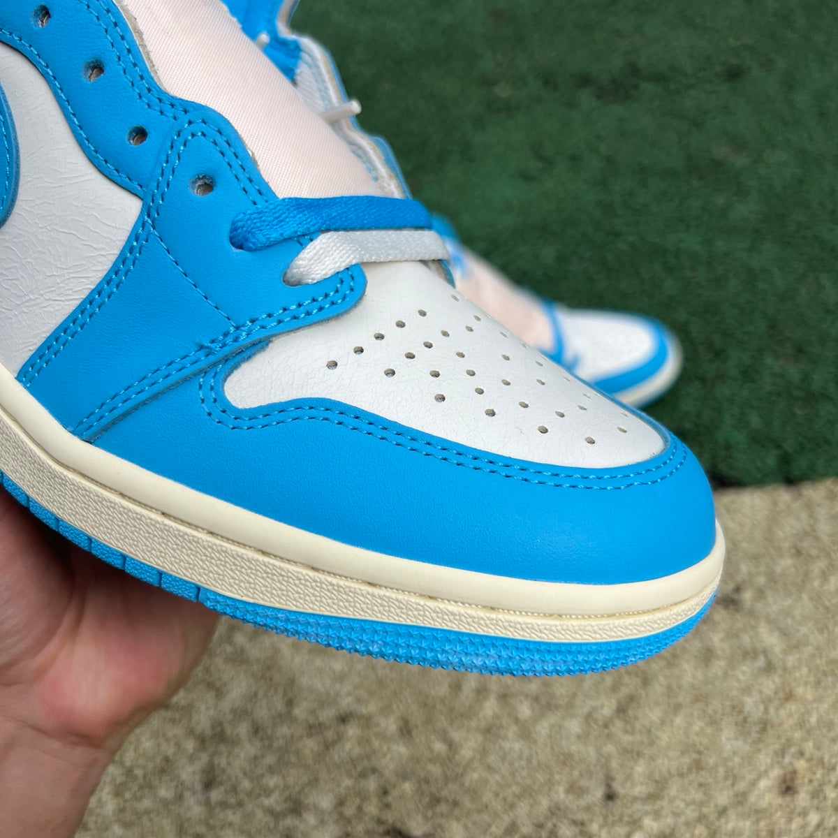 Nike Air Jordan 1 Retro High OG UNC Reimagined sneakers in white and light blue, featuring Nike and Jordan branding.