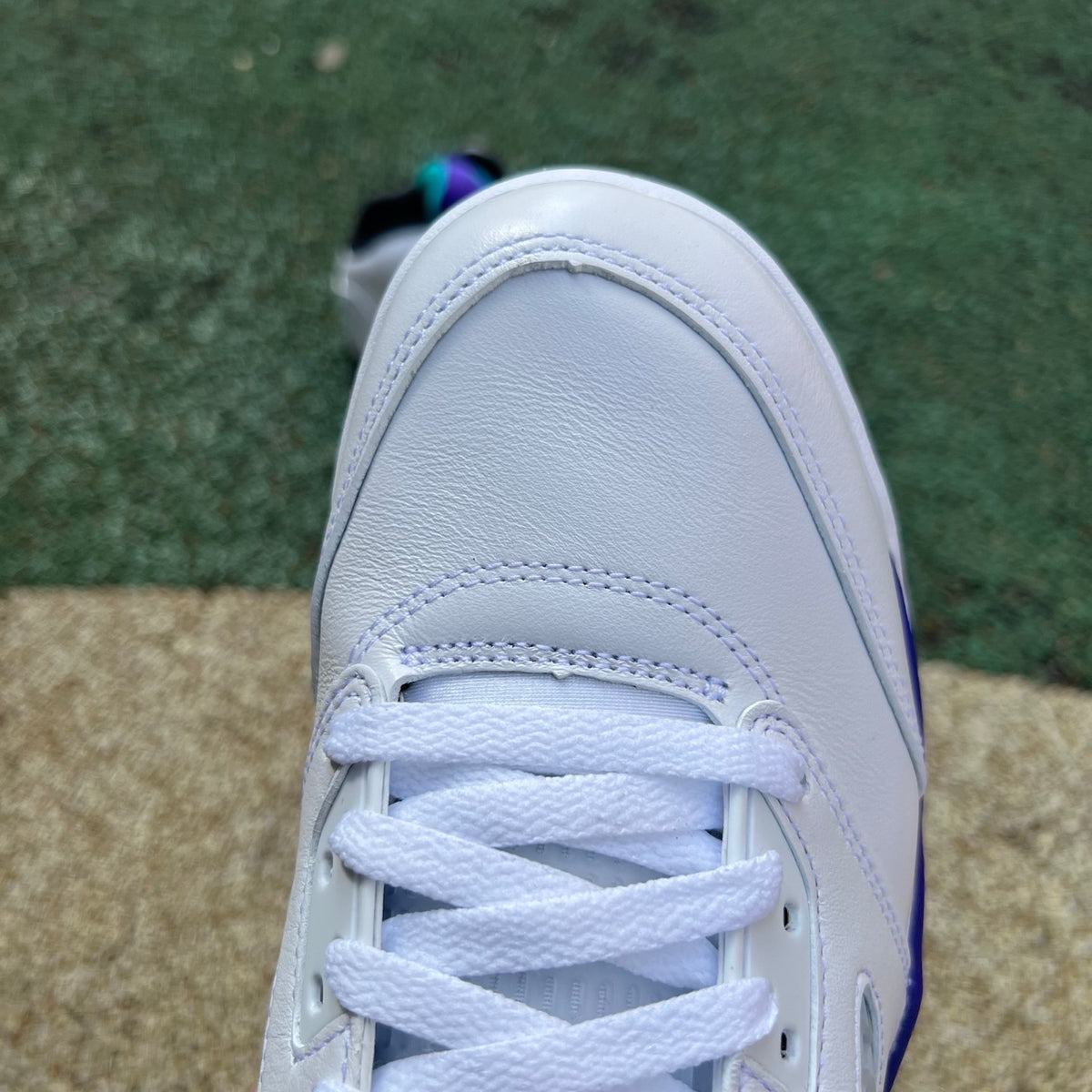 Close-up of Nike Air Jordan 5 Retro Grape sneakers in white, purple, and teal with detailed design and branding.