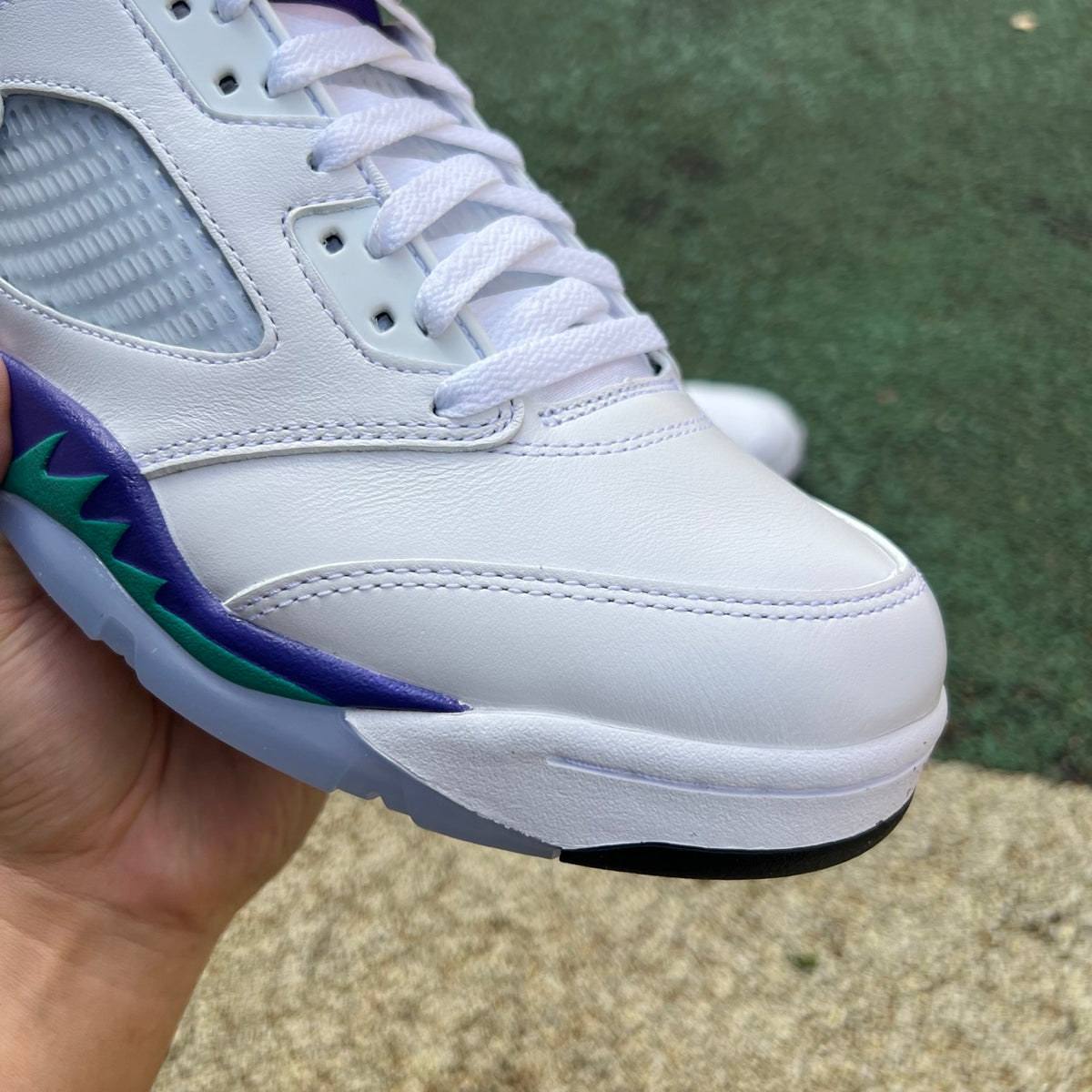 Close-up of Nike Air Jordan 5 Retro Grape sneakers with white, purple, and black colorway, featuring detailed design and branding.