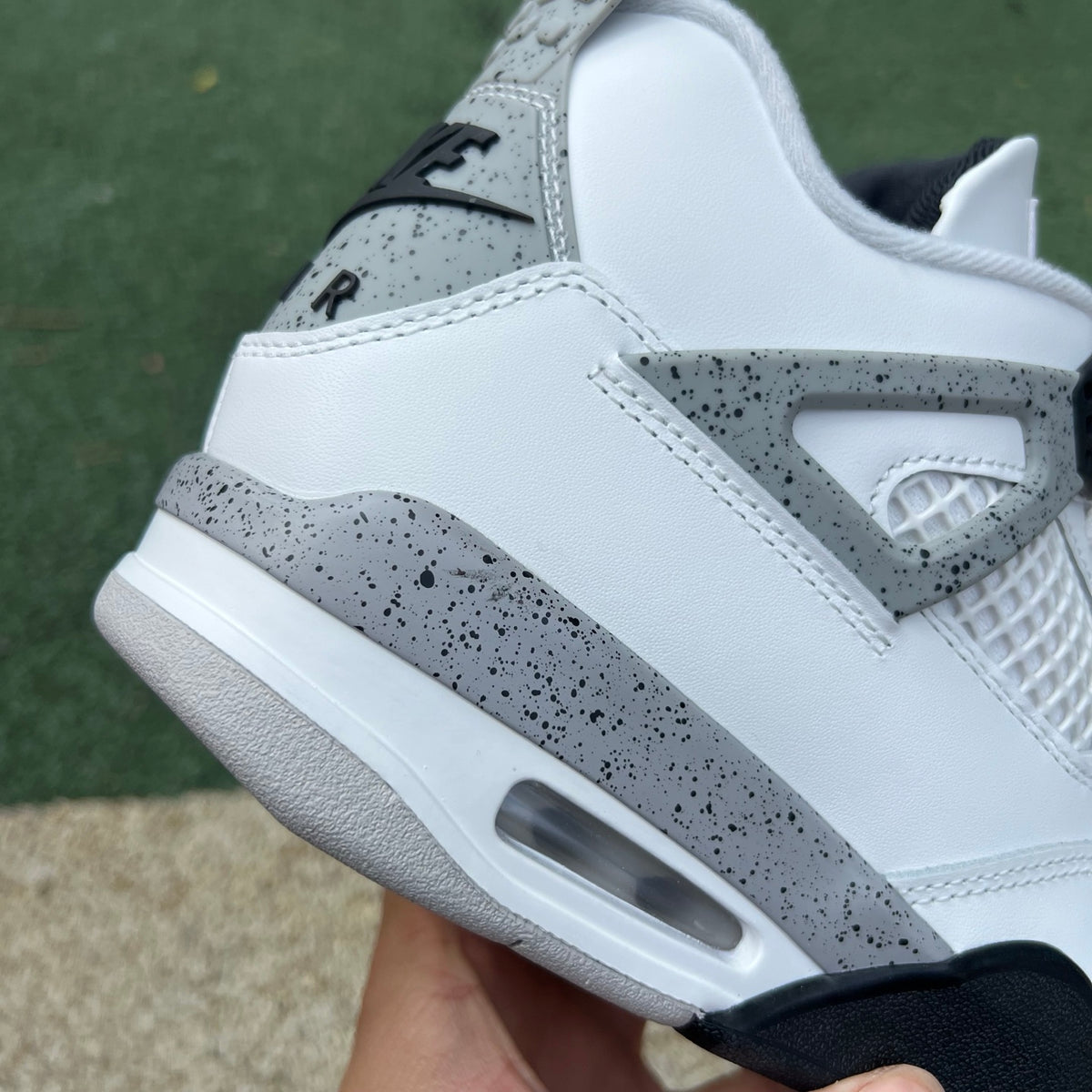 Nike Air Jordan 4 Retro White Cement sneakers in white with grey accents, featuring classic design and visible Air cushioning