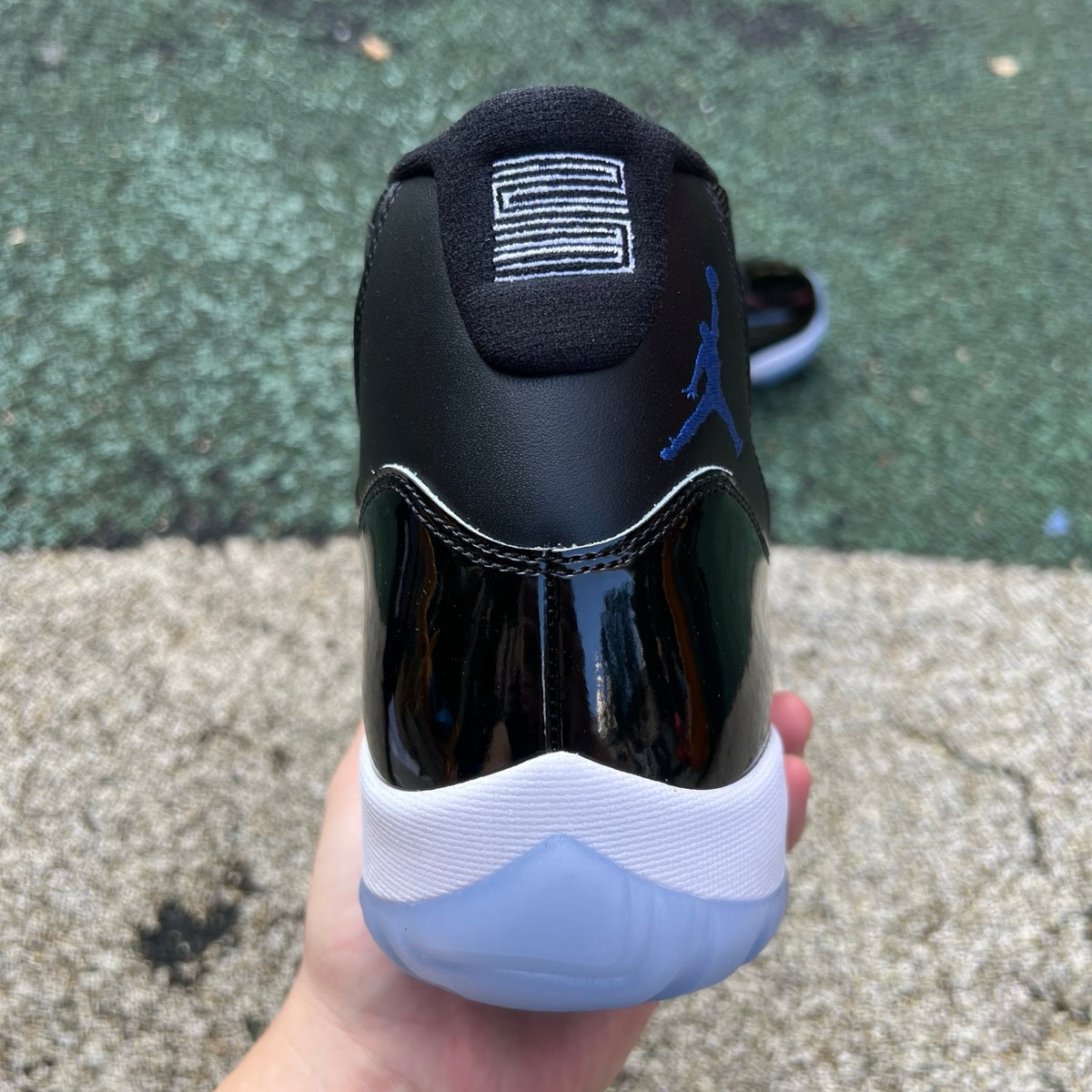 Nike Air Jordan 11 Retro Space Jam (2026) sneakers in black and patent leather with icy blue accents, front view.