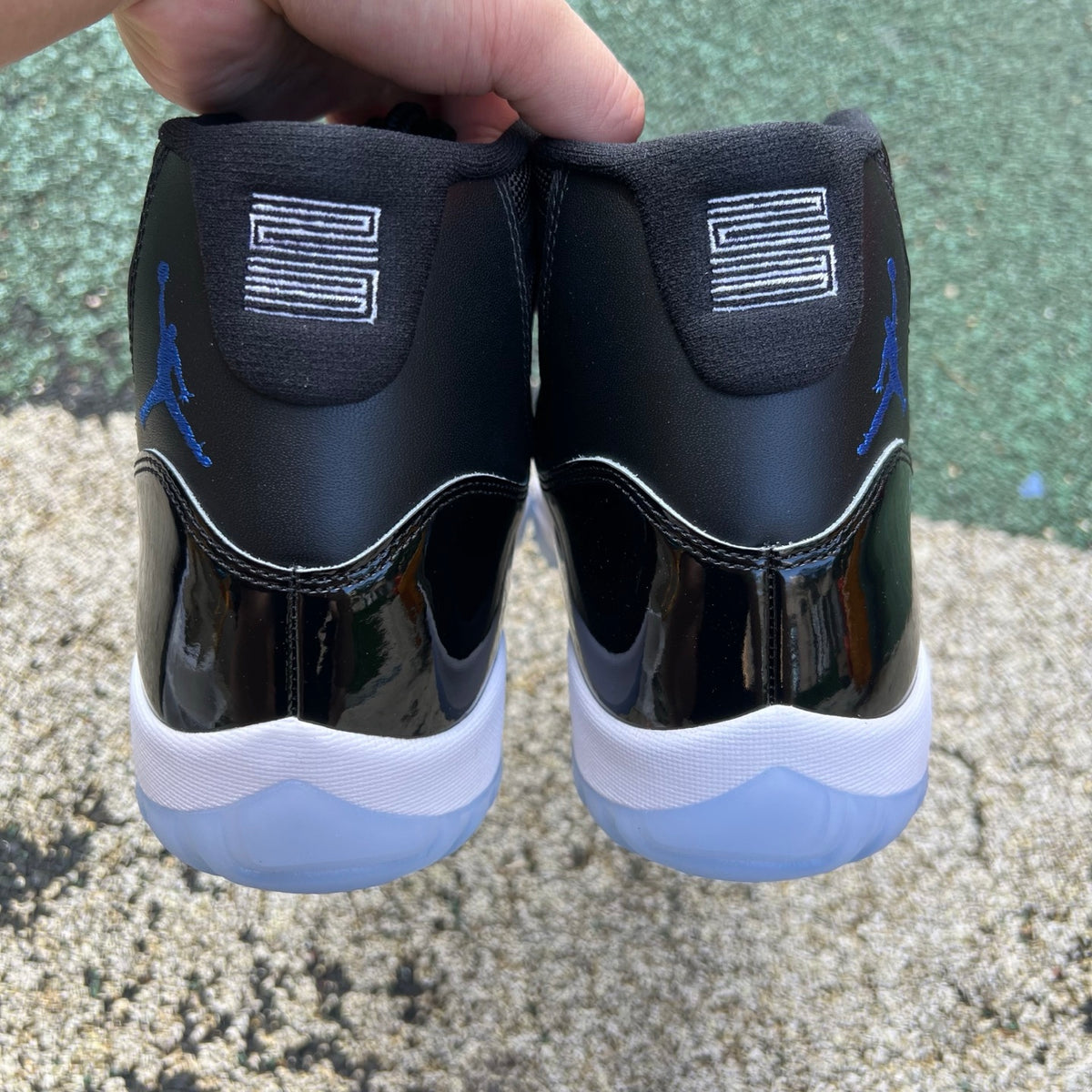 Nike Air Jordan 11 Retro Space Jam sneakers in black and blue with patent leather detailing, showcased from a side view.