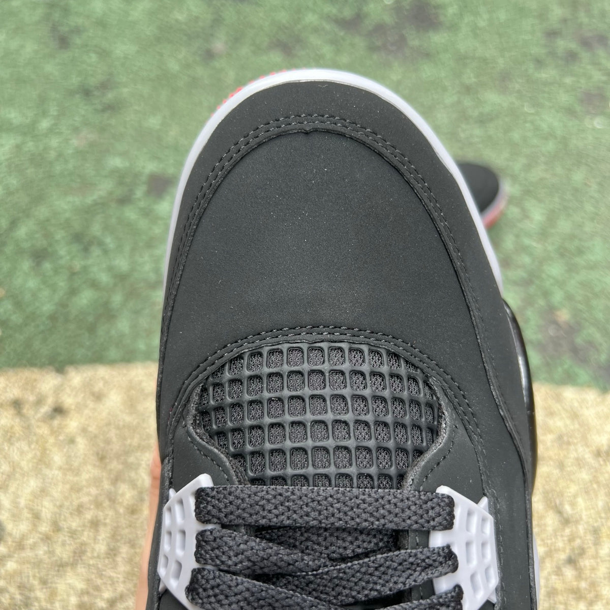 Nike Air Jordan 4 Retro OG Bred sneakers in black and red with white accents, featuring signature design details and Nike branding.