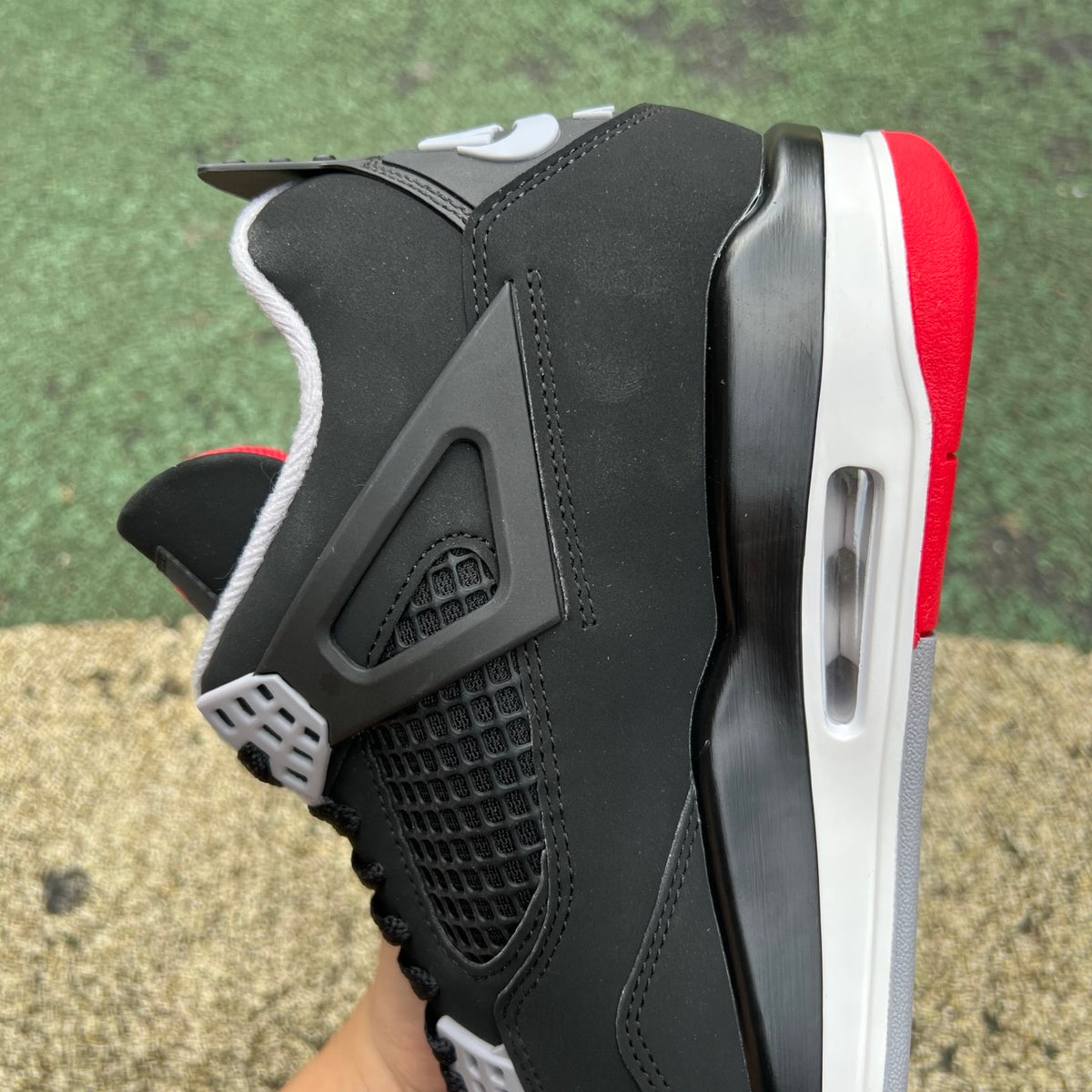 Nike Air Jordan 4 Retro OG Bred sneakers in black and red with white accents, showcasing the iconic basketball shoe design.