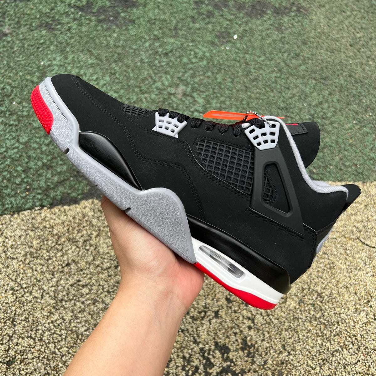 Nike Air Jordan 4 Retro OG Bred sneakers in black and red with white accents, displayed on a plain background.