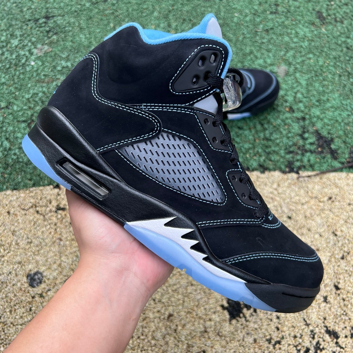 Nike Air Jordan 5 Retro sneakers in black and university blue, featuring a sleek design and iconic branding.