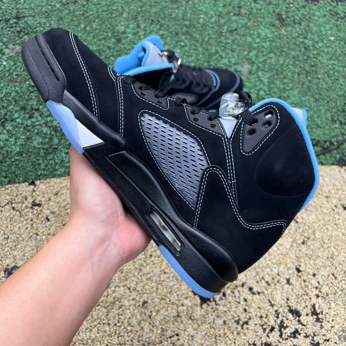 Nike Air Jordan 5 Retro sneakers in black and university blue with visible design details and branding on the side and sole.