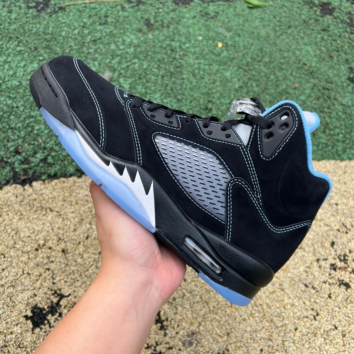 Nike Air Jordan 5 Retro sneakers in black with university blue accents, featuring a classic design and mid-top silhouette.