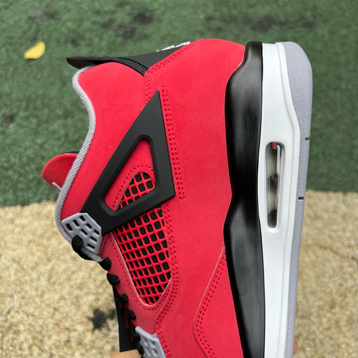 Nike Air Jordan 4 Retro Toro Bravo sneakers in red and black leather with white accents, showing side view and iconic design details.