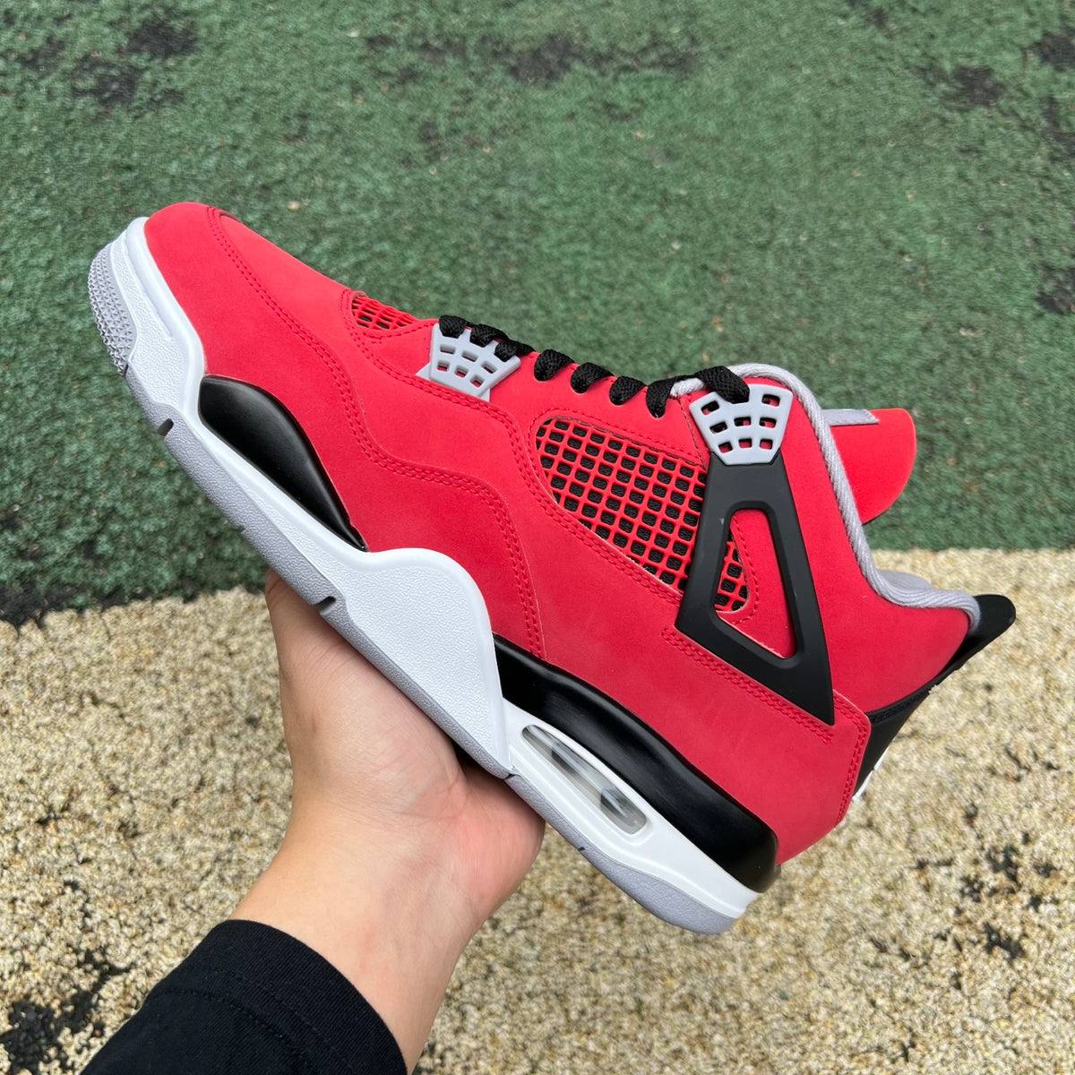 Nike Air Jordan 4 Retro Toro Bravo sneakers in red and black with white accents, displayed on a clean background.