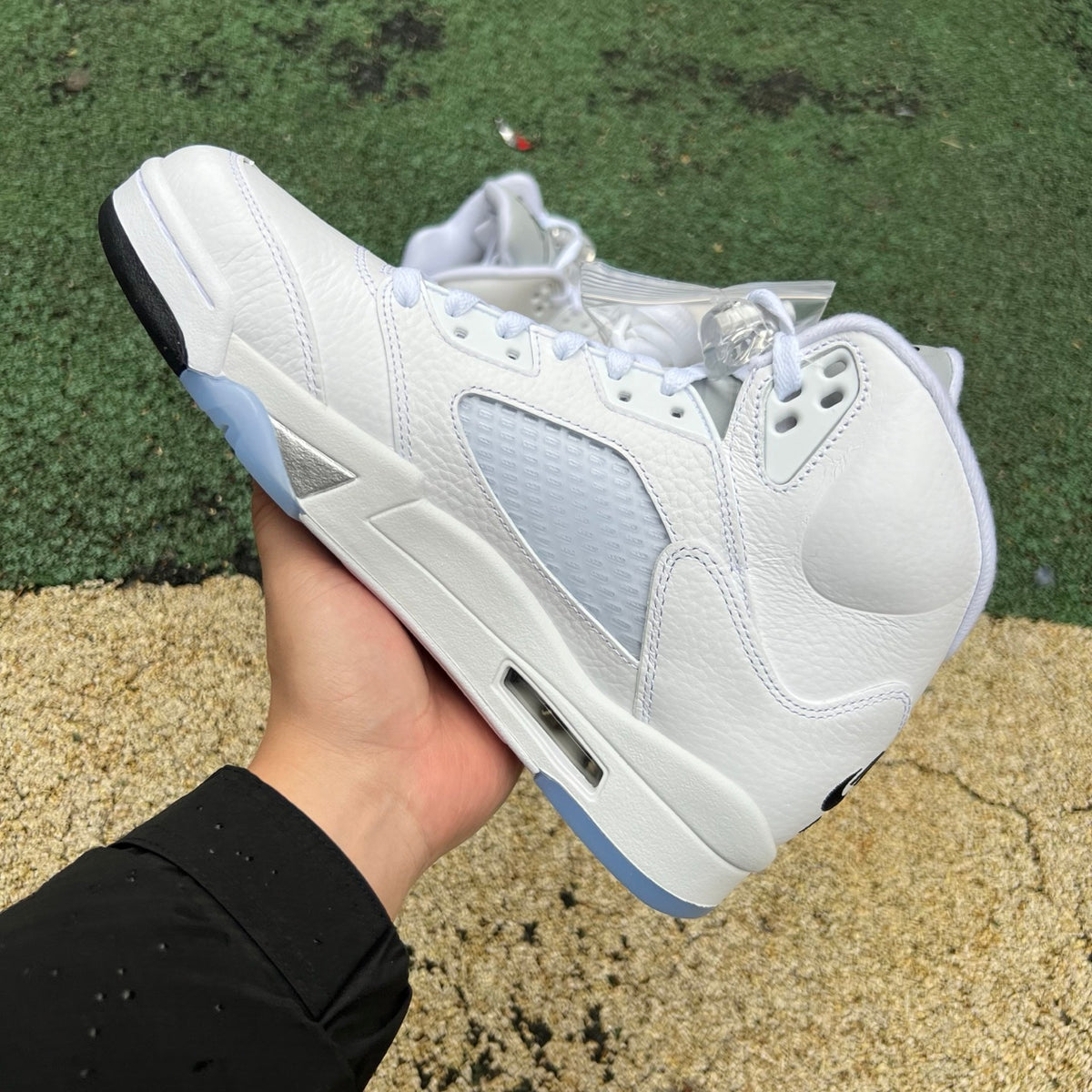 Nike Air Jordan 5 Retro White Metallic sneakers in close-up, showing the sleek white and metallic silver design details.