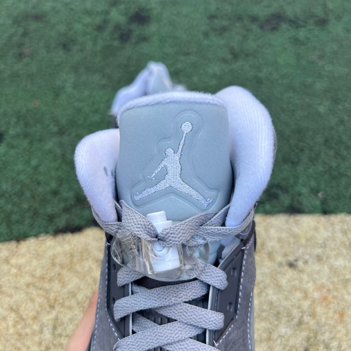 Nike Air Jordan 5 Retro Wolf Grey sneakers featuring grey and black leather, visible air cushioning and signature design details.