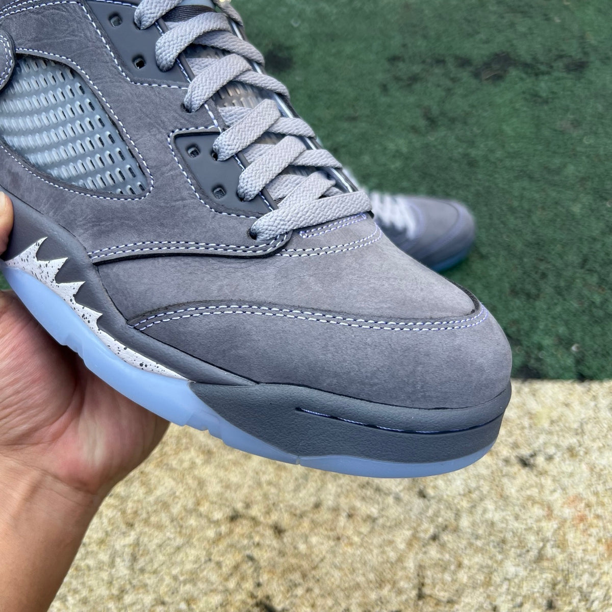 Nike Air Jordan 5 Retro Wolf Grey sneakers in close-up, showing the grey suede and signature design details.