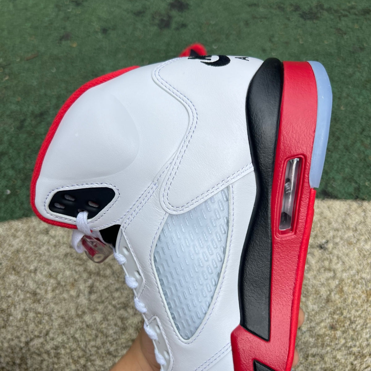 Nike Air Jordan 5 Retro Fire Red and black sneakers with a prominent tongue and classic design, shown from a side view.