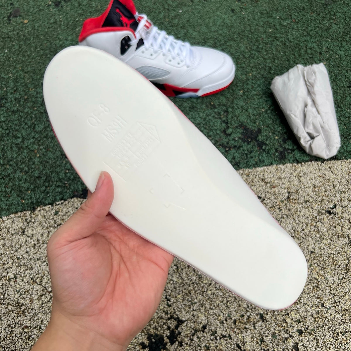 Nike Air Jordan 5 Retro Fire Red and black sneakers featuring a prominent tongue and stylish design, shown from a side view.