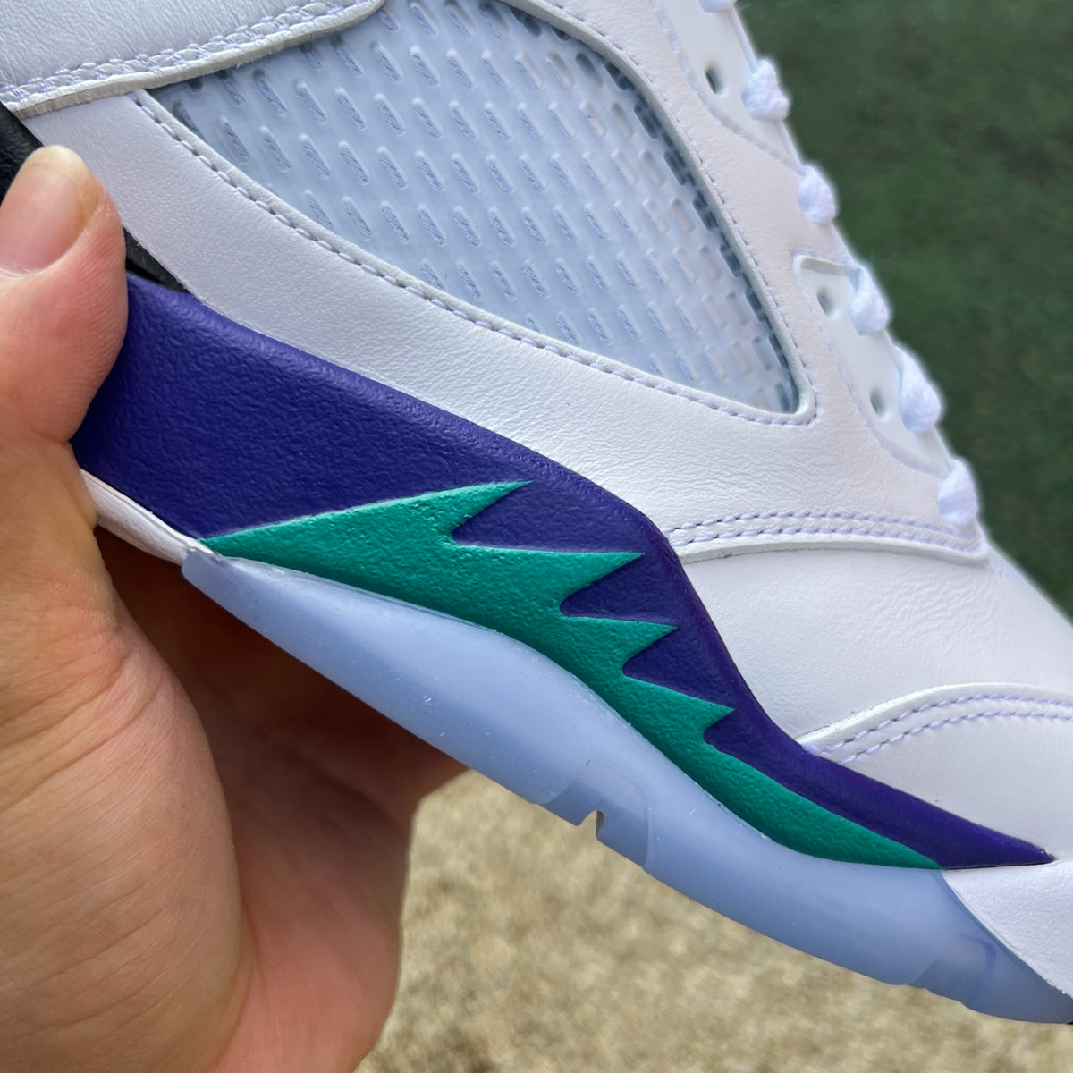 Nike Air Jordan 5 Retro Grape sneakers in white, purple, and teal with a close-up view of the shoe's side and textured design.
