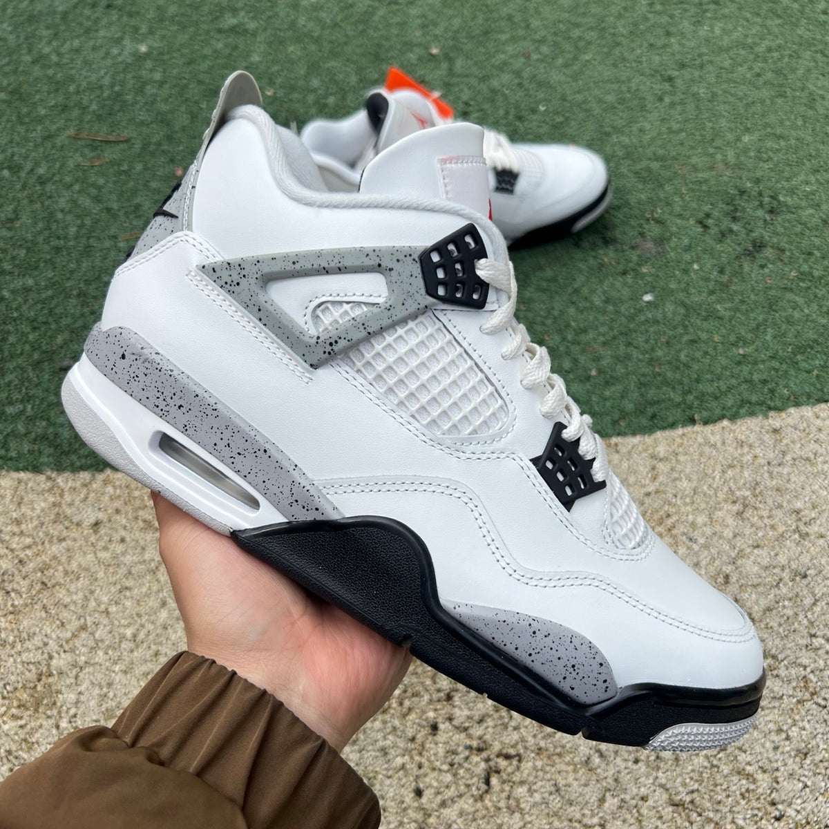 White Nike Air Jordan 4 Retro sneakers with cement accents, featuring a classic design and Nike x Jordan branding.