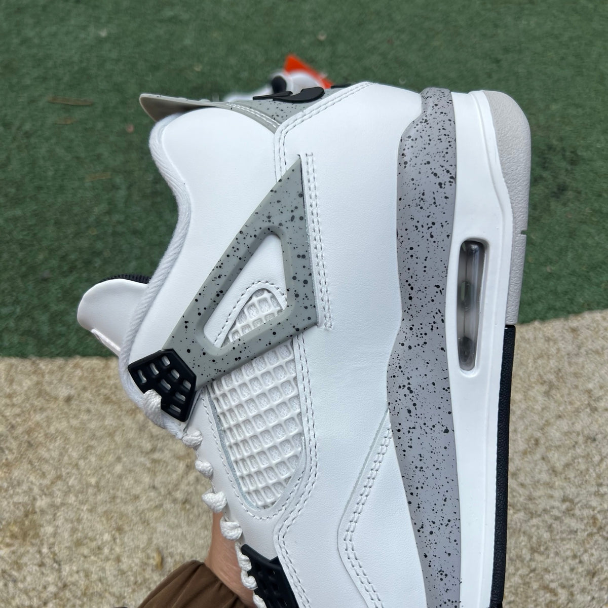 Nike Air Jordan 4 Retro White Cement sneakers in white with grey accents, featuring classic design and branding details.
