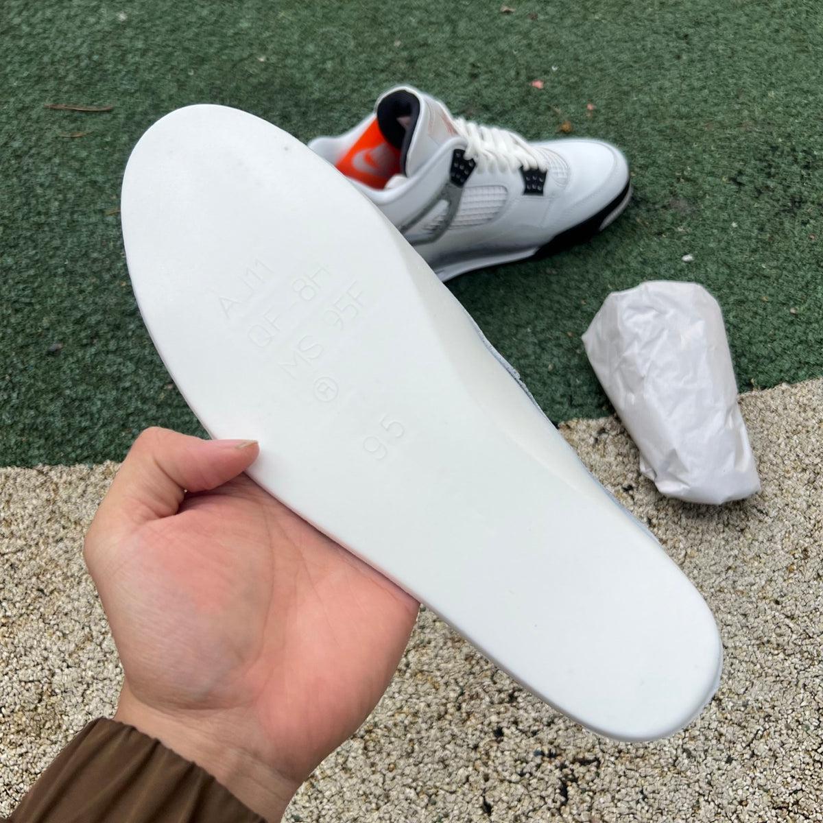 Nike Air Jordan 4 Retro White Cement sneakers in white and grey with red accents, showcasing the iconic design and textured materials.