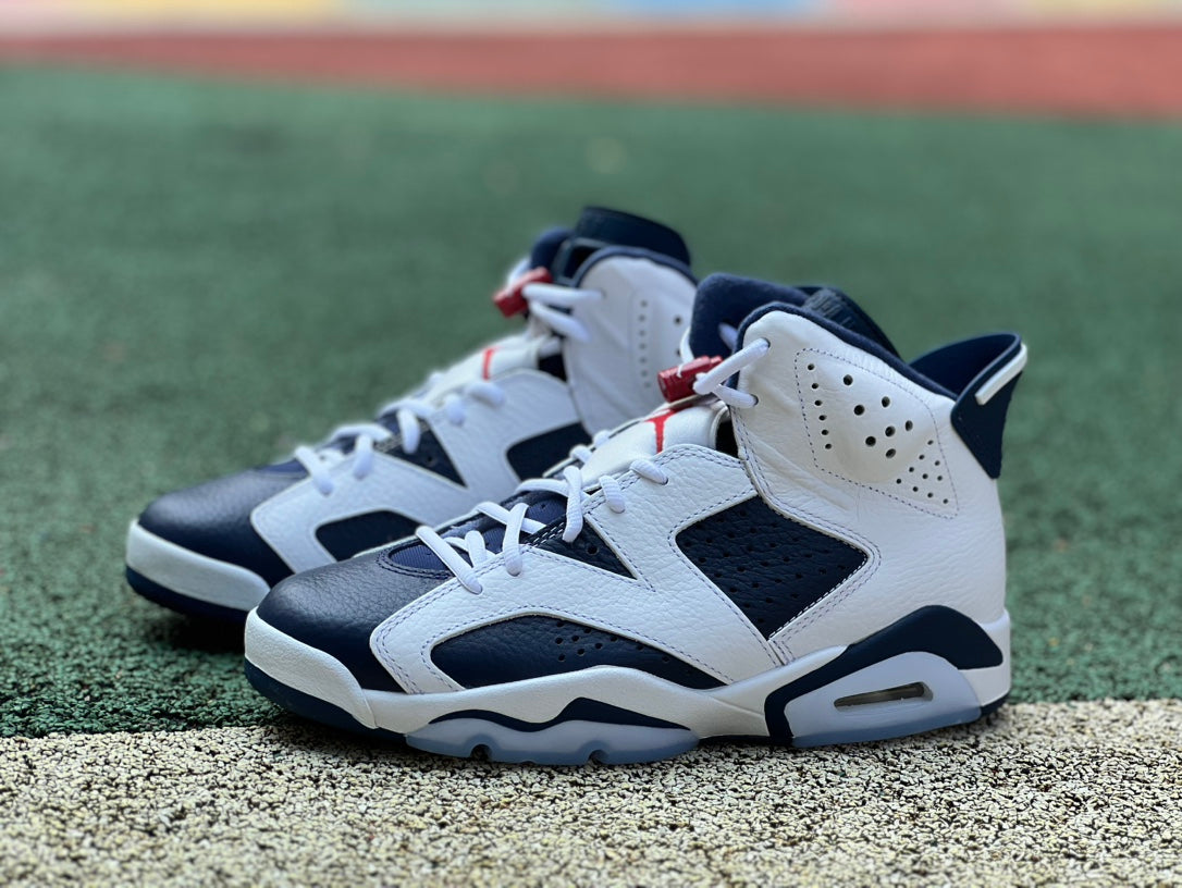 Nike Air Jordan 6 Retro Olympic sneakers in white, blue, and gold with Nike and Jordan branding, featuring a sleek athletic design.