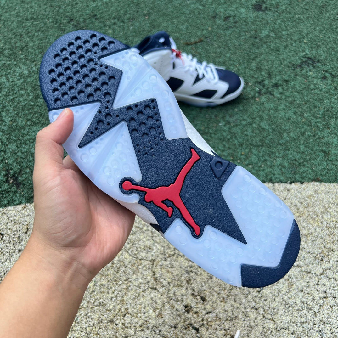 Nike Air Jordan 6 Retro Olympic sneakers in white, blue, and gold with Nike and Jordan branding, featuring a classic basketball shoe design.