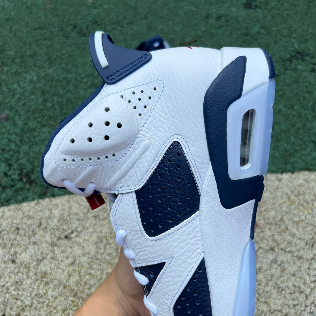 Nike Air Jordan 6 Retro Olympic sneakers in white, blue, and gold with Nike branding and signature design details.
