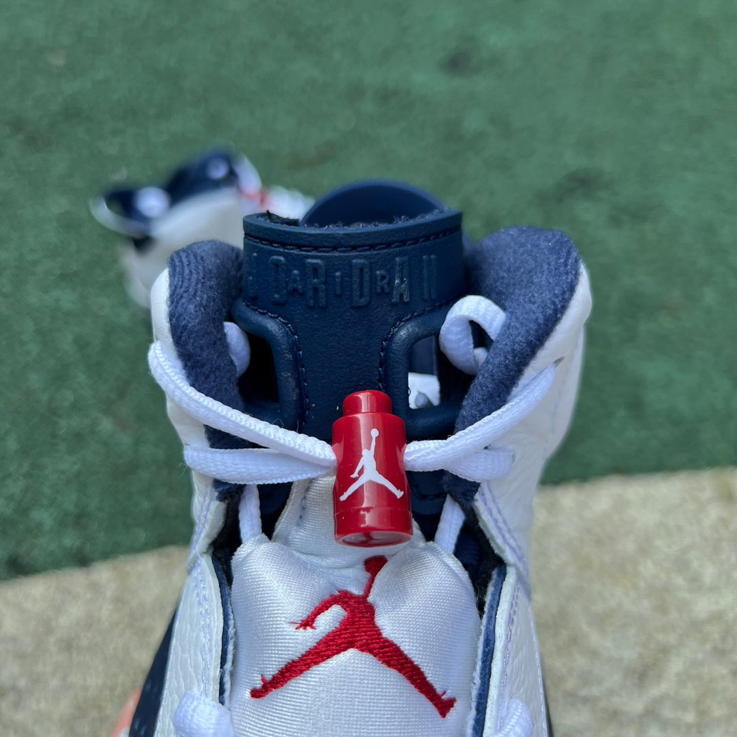 Nike Air Jordan 6 Retro Olympic sneakers in blue, white, and gold with a sleek design and signature Jumpman logo.