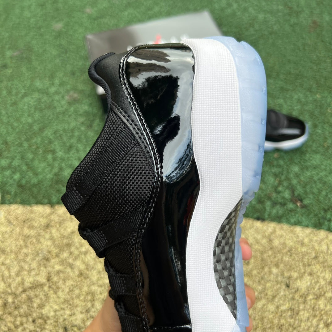 Nike Air Jordan 11 Retro Low Space Jam sneakers in black and blue with icy translucent outsole, Nike x Jordan branding visible.